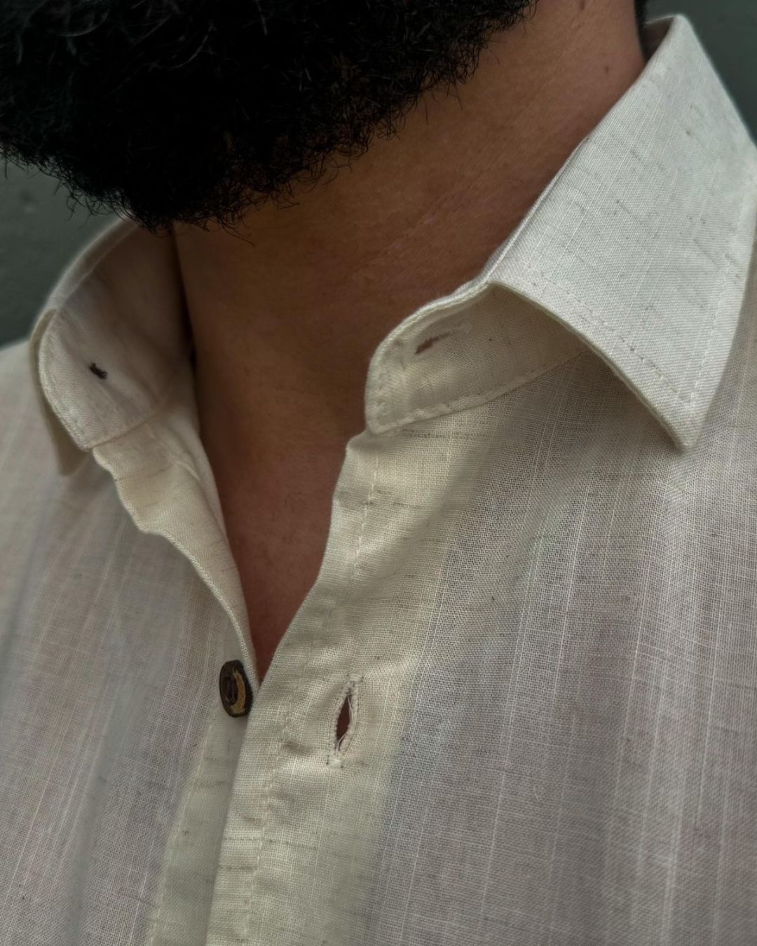 homem-usando-camisa-de-linho-bege-manga-curta-com-botoes-escuros-em-ambiente-urbano