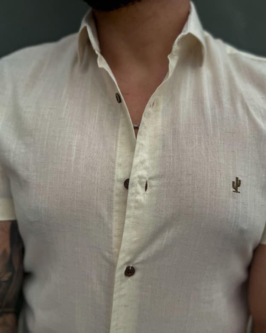 homem-usando-camisa-de-linho-bege-manga-curta-com-botoes-escuros-em-ambiente-urbano