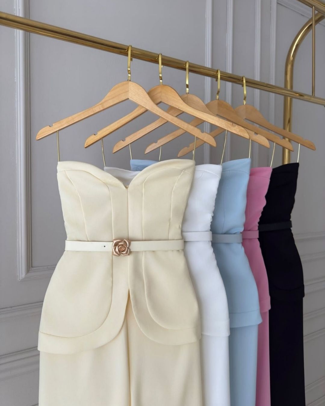 mulher-usando-macacao-tomara-que-caia-com-cinto-fino-e-calca-pantalona-segurando-clutch-branca-em-ambiente-elegante-amarelo