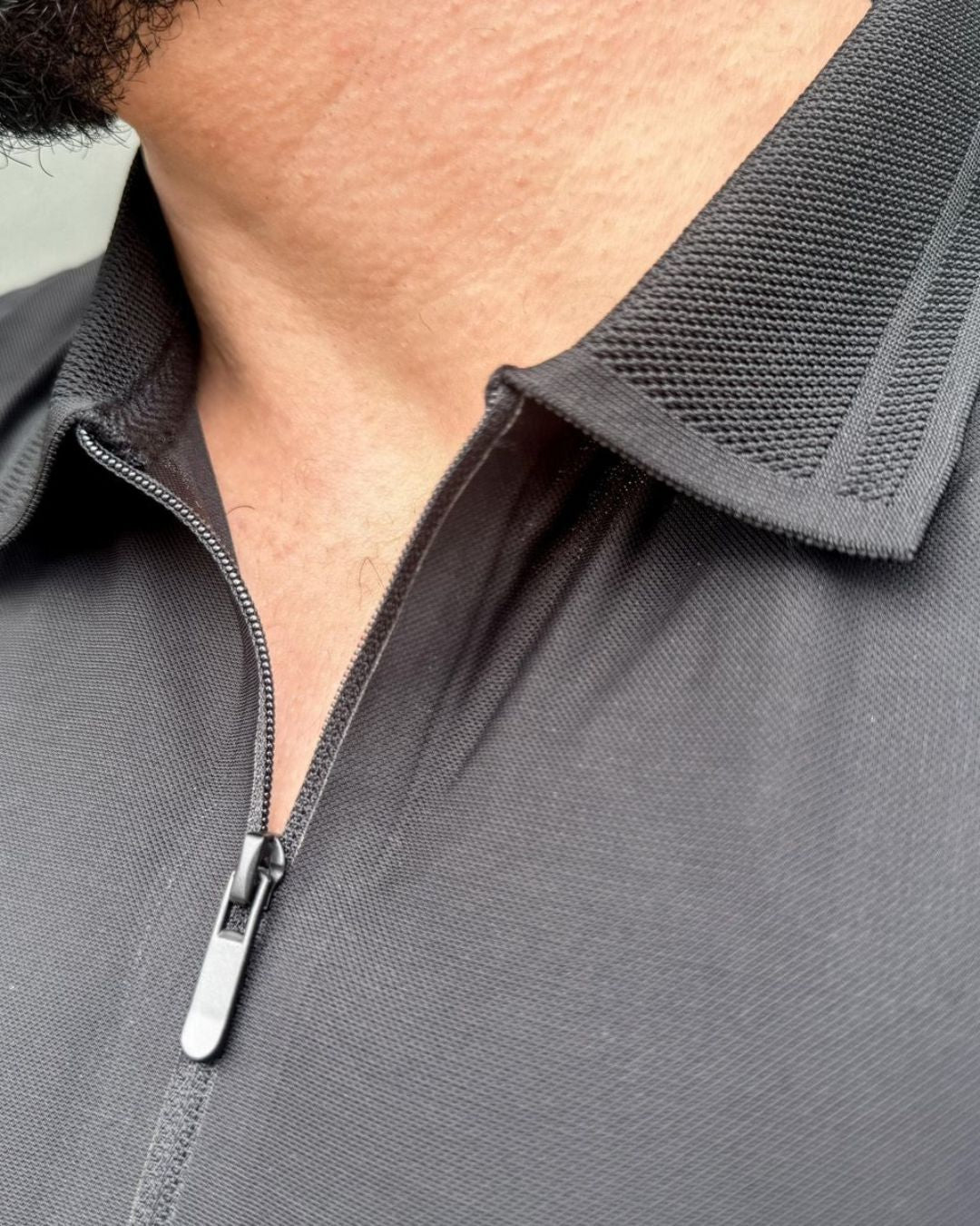 homem-usando-camisa-polo-preta-manga-curta-com-ziper-modelo-jacquard-em-ambiente-urbano