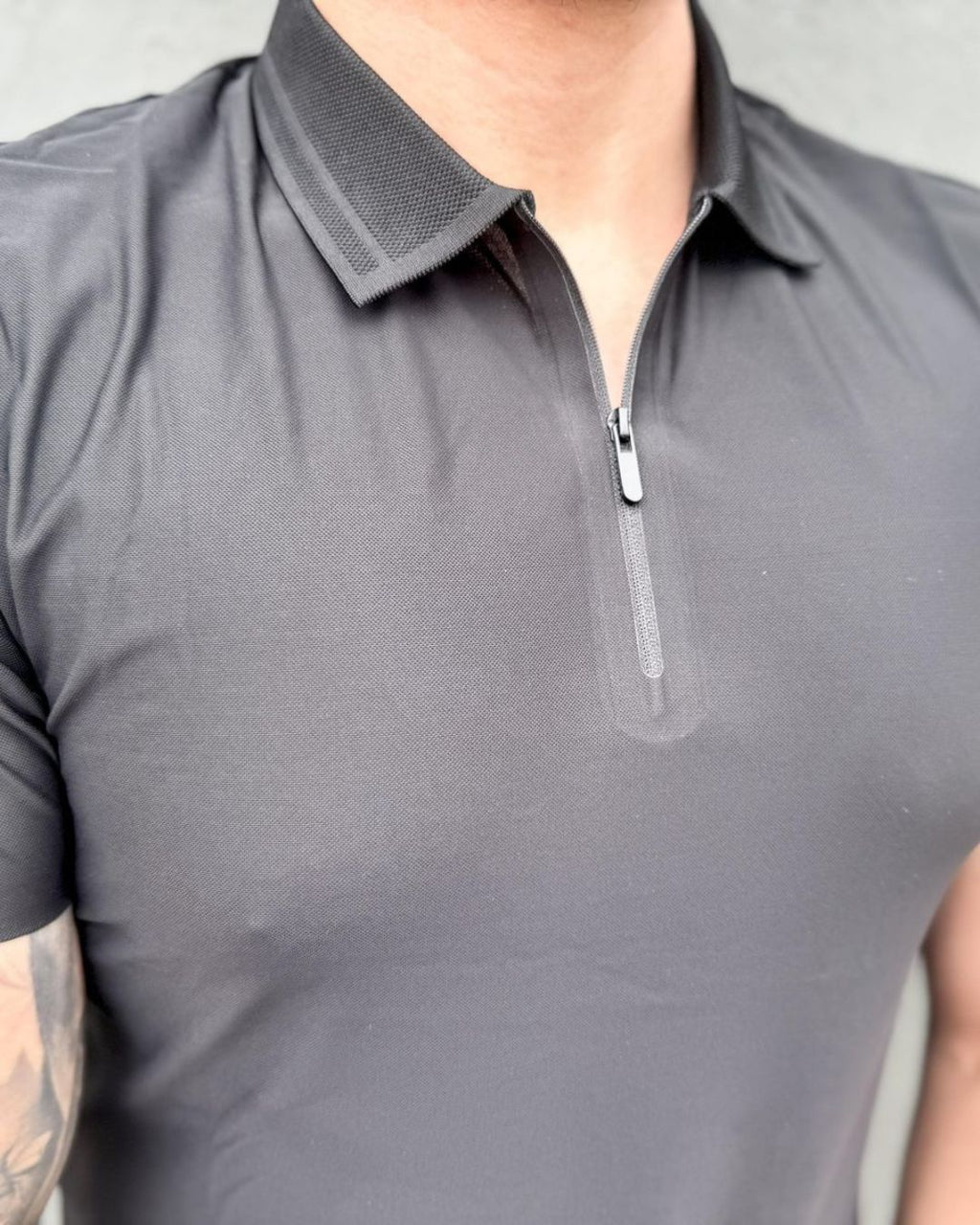 homem-usando-camisa-polo-preta-manga-curta-com-ziper-modelo-jacquard-em-ambiente-urbano